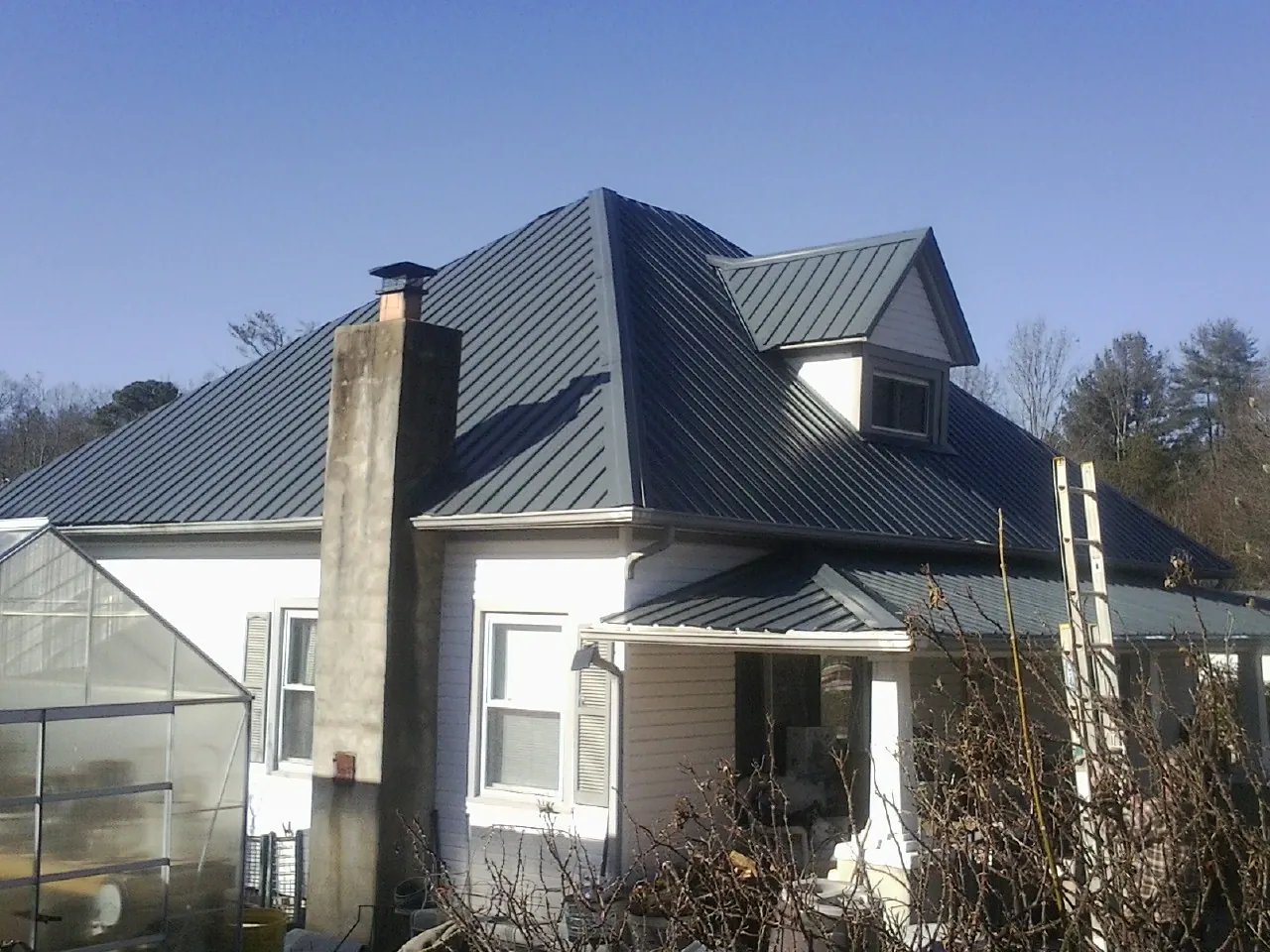 Dark blue standing seam metal roof on a white farmhouse with dormer — Slate & Tile Roof Repair by Roofing Brothers in Oldwick