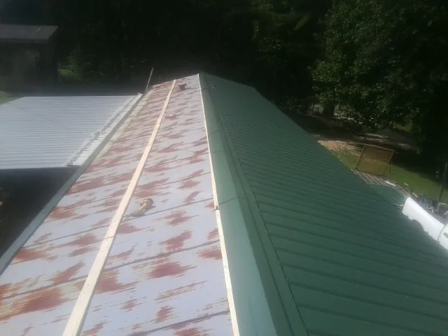 Old rusted panels beside newly installed green metal roofing — Wind Damage Roof Repair by Roofing Brothers in Oldwick