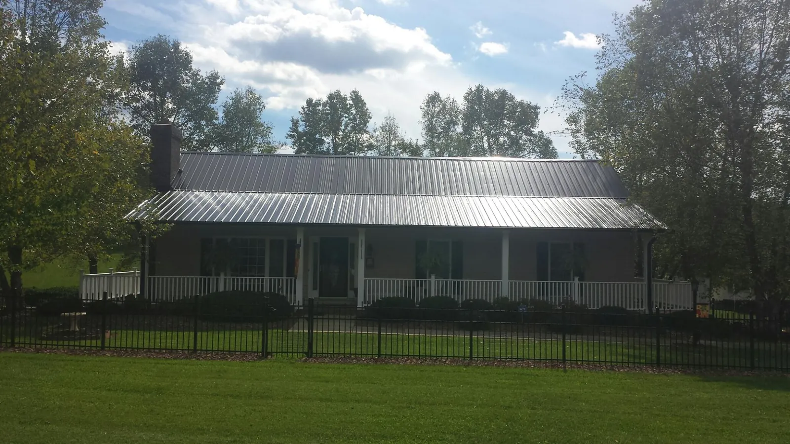 Gray metal roof on a brick ranch with a full width front porch — Gutter Guard Installation work by our crew in Oldwick